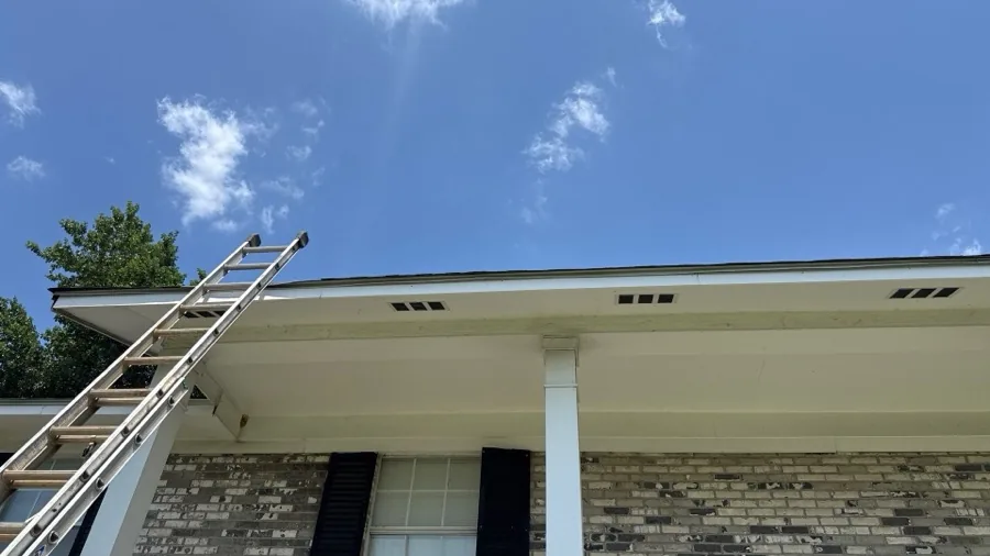 Gutter line along the eave of a home, with a ladder set up for roof work