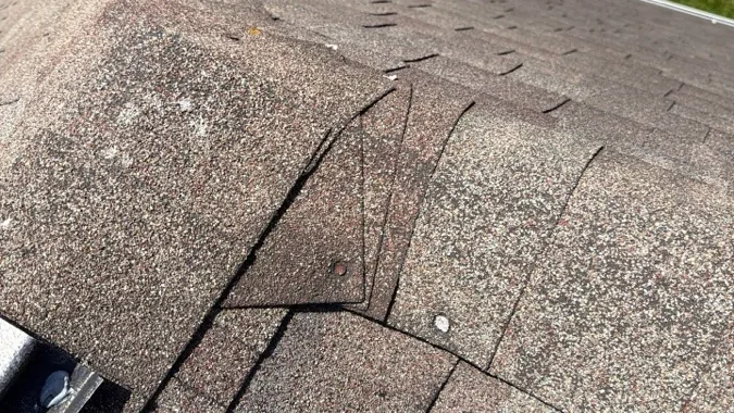 Creased asphalt shingle, one of the warning signs of roof damage